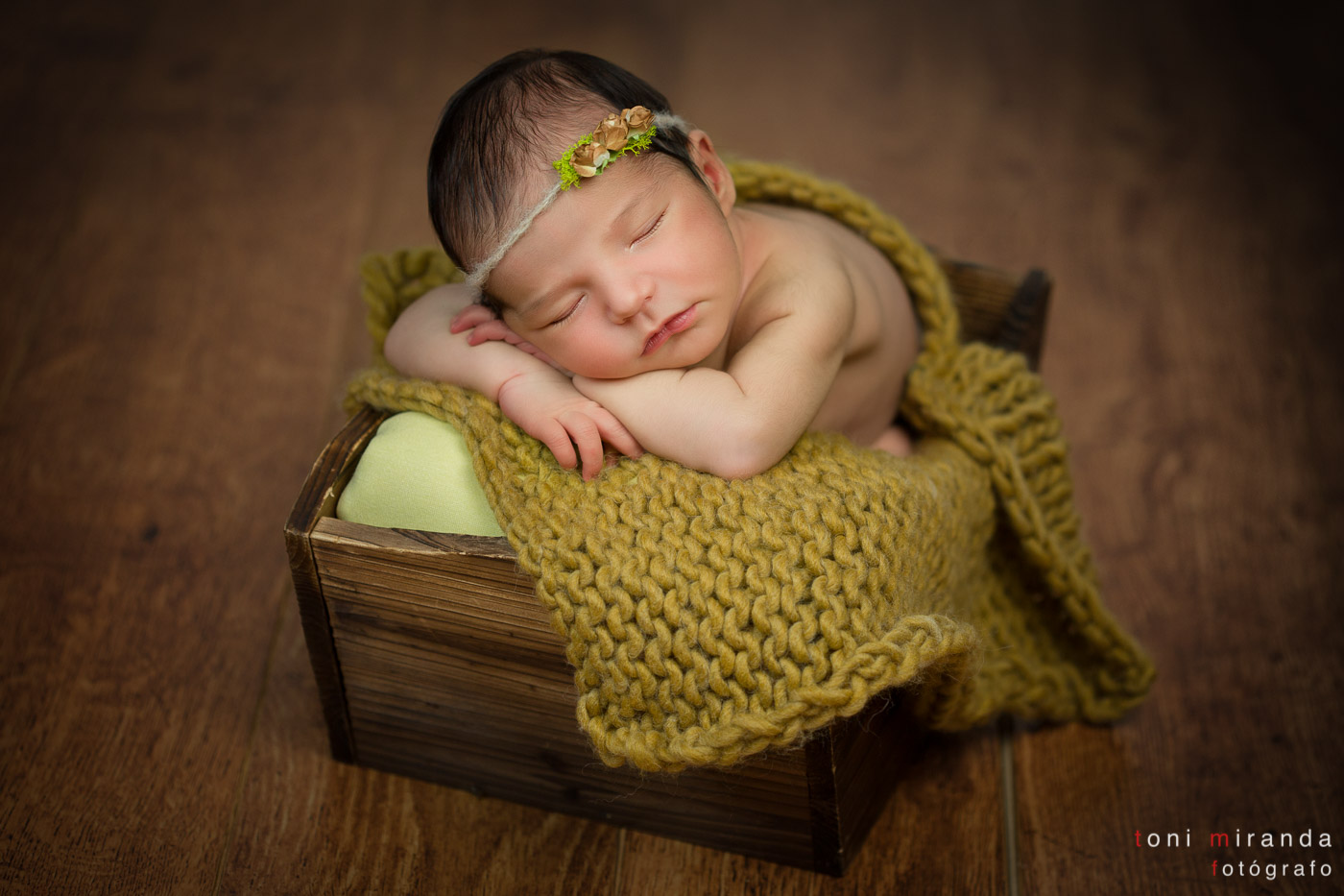 bebe recien nacido durmiendo en caja de madera con flores en la cabeza