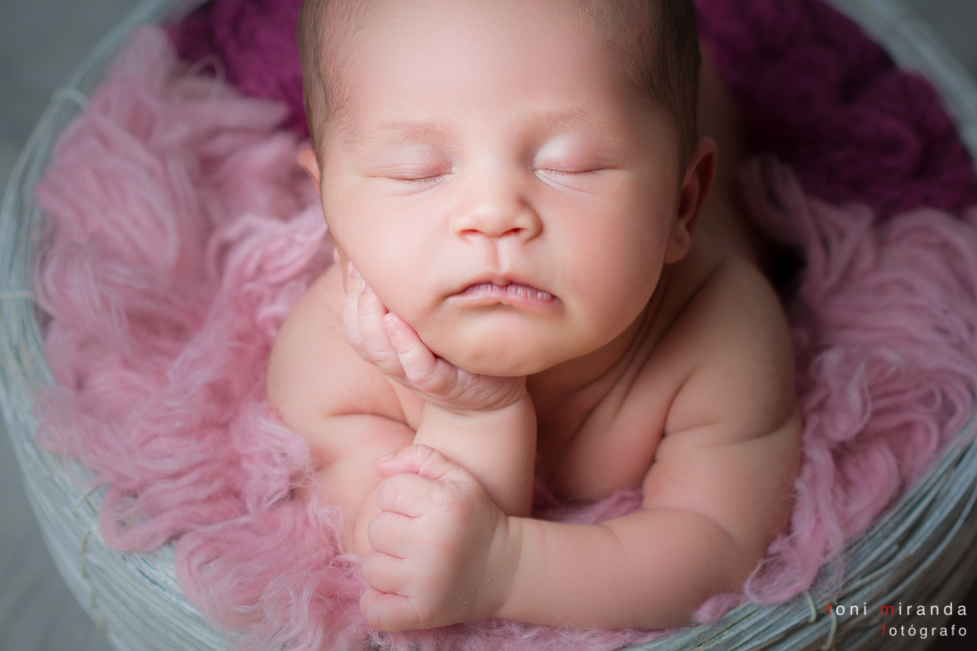 Bebe newborn recien nacido en cesta de mimbre gris en sesion de estudio fotografico Alcoy