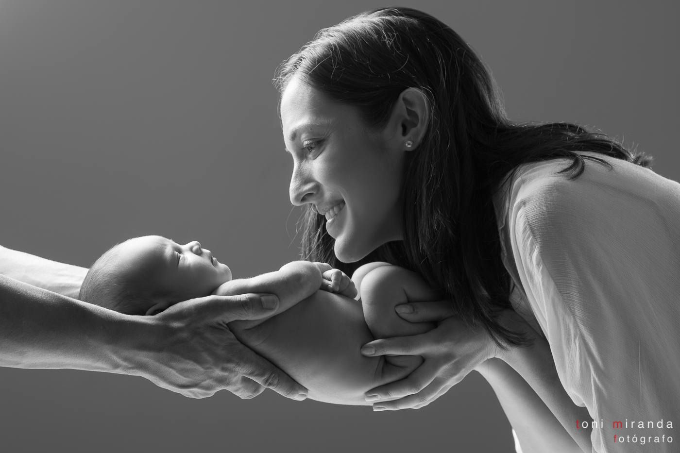 Bebe newborn en brazos de madre y padre en estudio fotográfico Toni MIranda de Alcoy