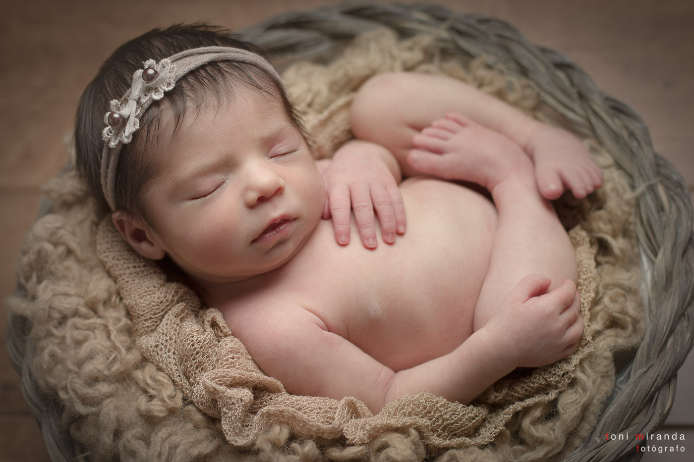 bebe recien nacido durmiendo en cesta con diadema en sesión fotográfica en estudio de alcoy en alicante