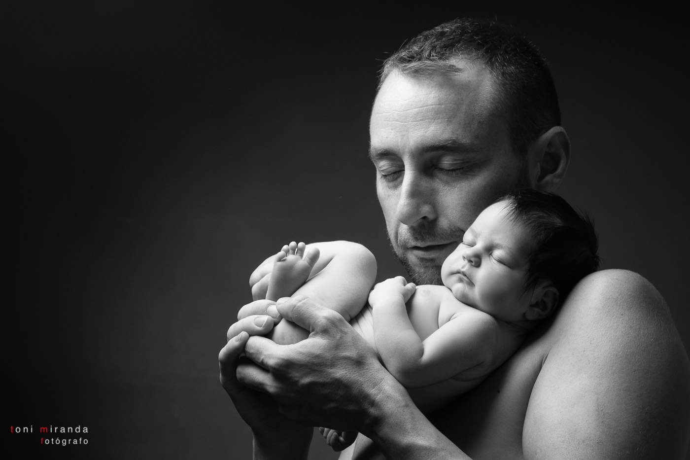 Padre sujetando a su recien nacida mientras duerme